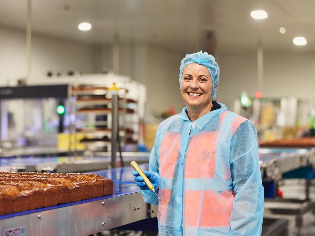 Smiling baker holding a temperature probe in commercial bakery