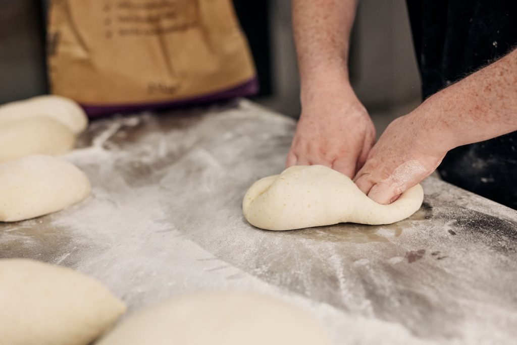 A person kneading doigh on a table covered in white flour