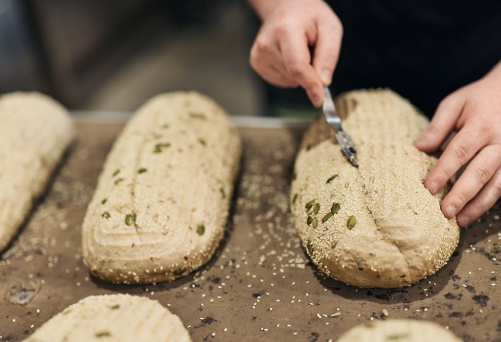 A person provnig bread on a wooden table